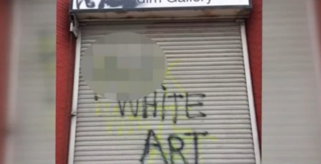 Courtesy of NBC LA. Vandalized garage door of Nicodim Gallery in Boyle Heights, with the words "expletive" white art spray painted on.