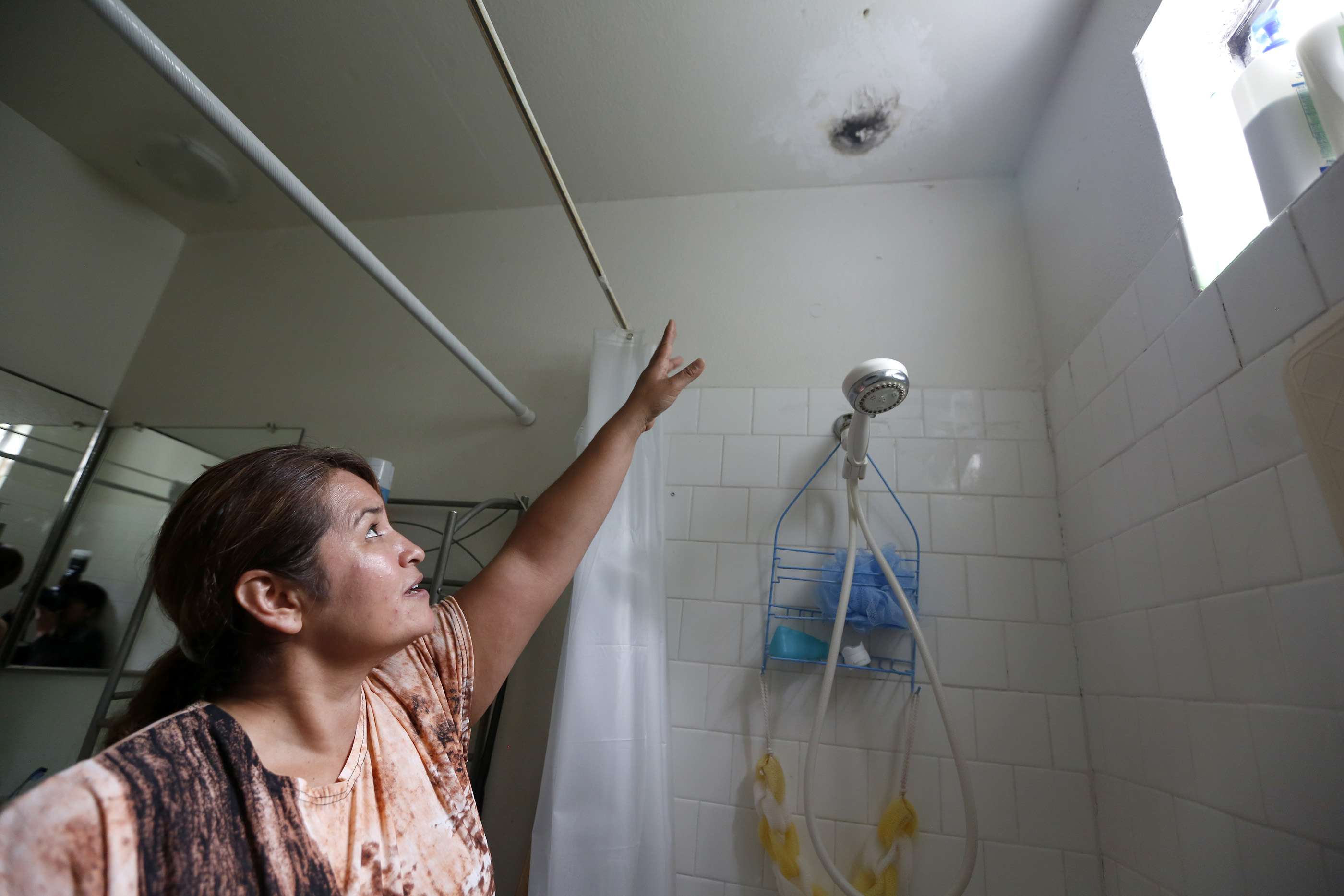Oralia Juárez, una de las residentes del edificio, muestra una gotera con moho que hay en su departamento. (Foto: Aurelia Ventura/La Opinión)