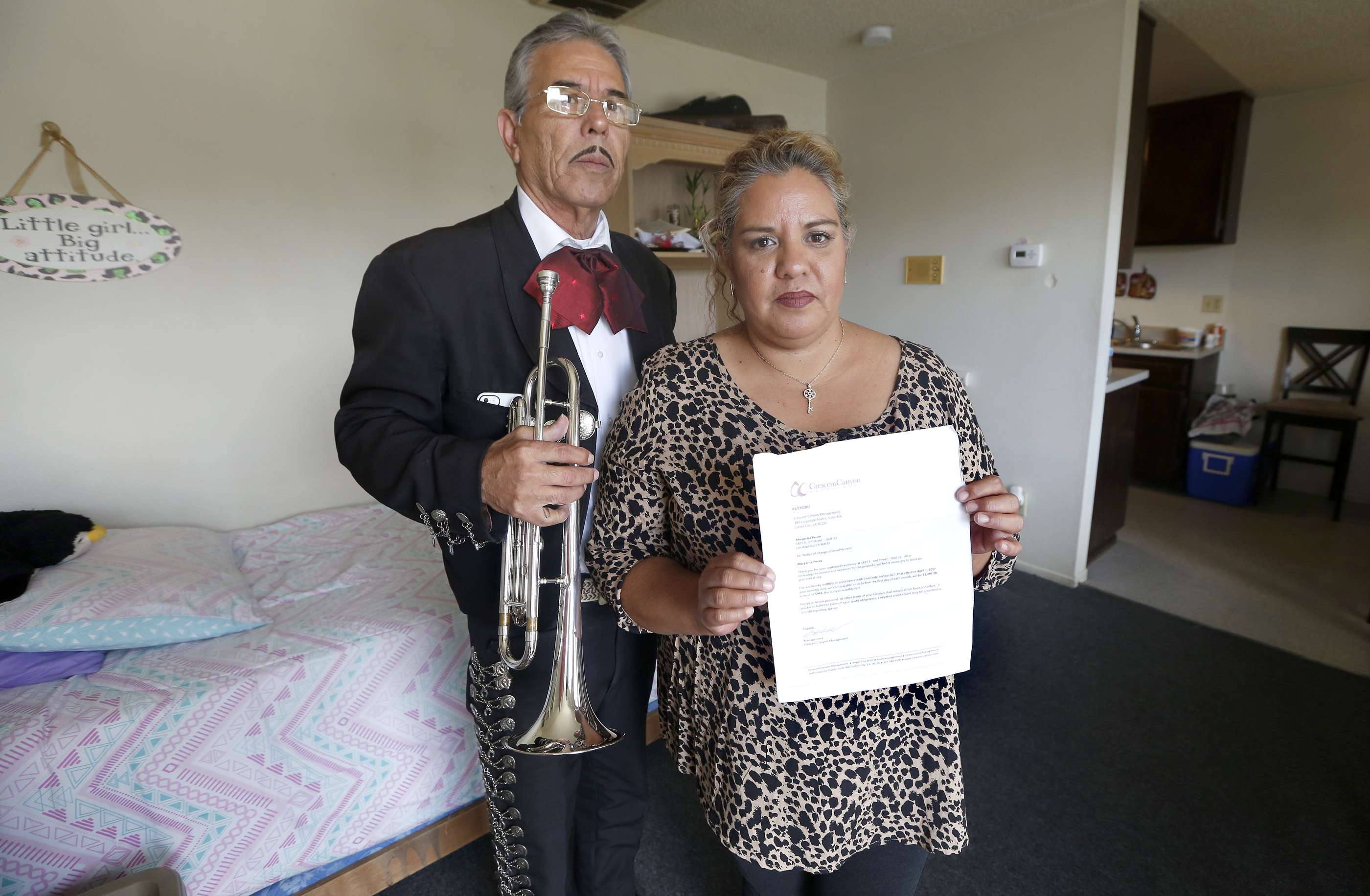 Margarita Perea (i) muestra la notificación de subida de alquiler. Asegura que de mudarse su esposo Pedro Zúñiga (d) quien es mariachi se verÃa afectado en su trabajo. (Foto: Aurelia Ventura/La Opinión)