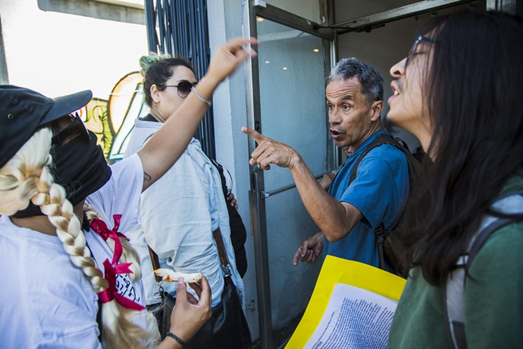 A customer argues with anti-gentrification protesters at the entrance to Weird Wave Coffee on Saturday