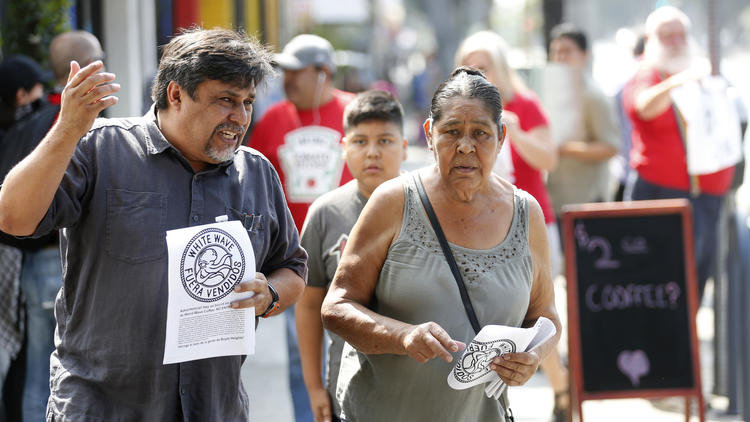 Leonardo Vilchis, left, hands out fliers against Weird Wave Coffee in Boyle Heights in June. "There is a trend of people being pushed out," Vilchis said. (Gary Coronado / Los Angeles Times)